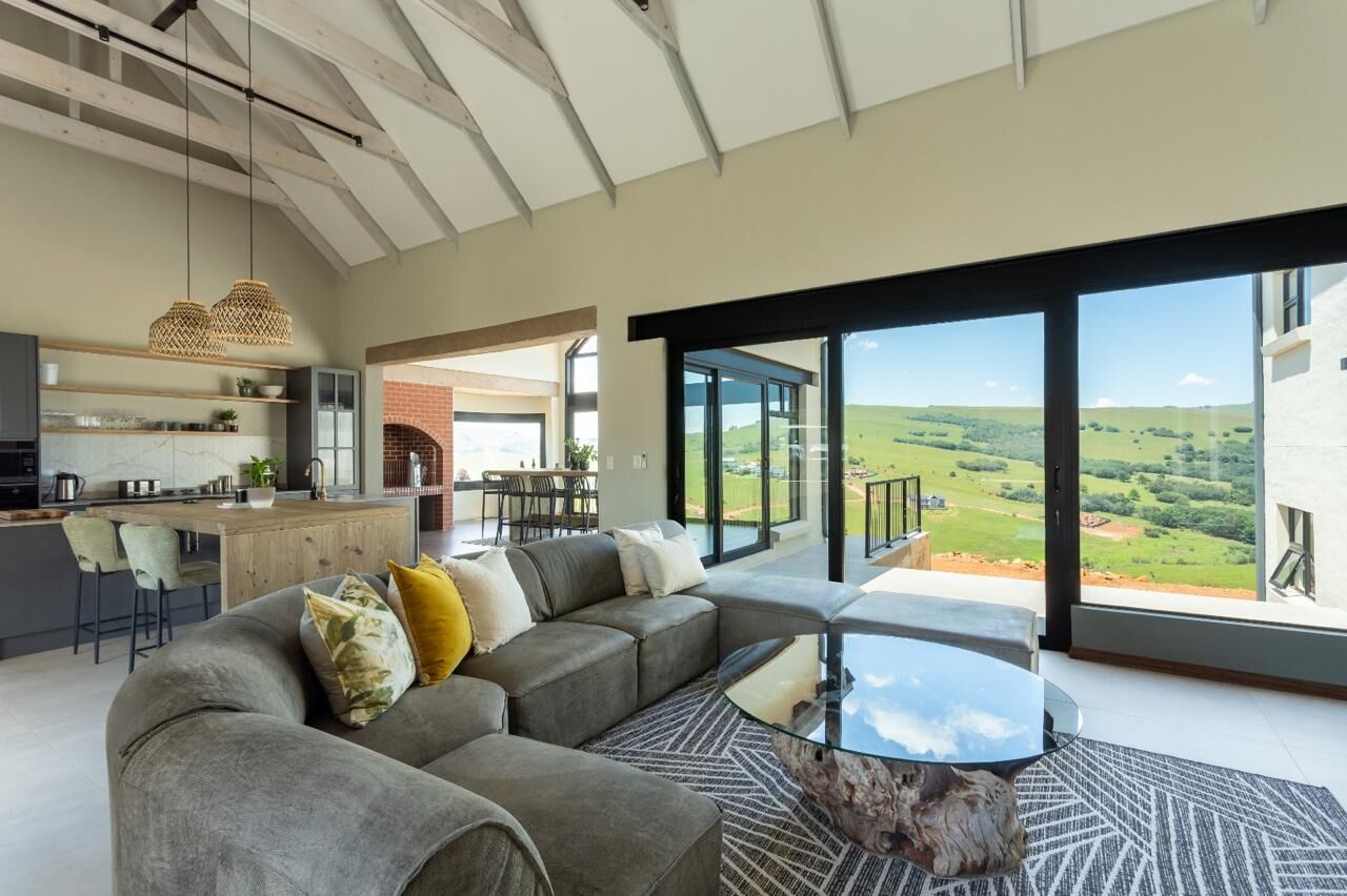 Lounge with large grey sofa, glass coffee table and sliding doors to the valley view
